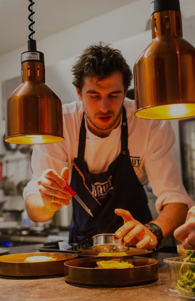 Site do Sabor & Cia — chef finalizando pratos sob luminárias de cobre